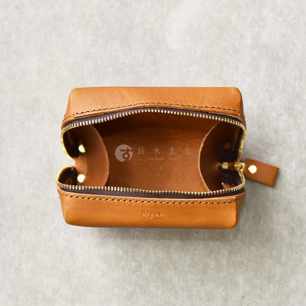 職人手作皮革Organ箱型收納包，材質為淺棕色皮革，拉鍊處為金色，包身有SUZUKI SHOP字樣。