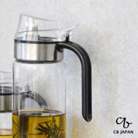 CB JAPAN atomico系列耐熱防回流玻璃油罐，罐內裝有金黃色食用油，並浸泡著幾枝迷迭香，搭配黑色手把。