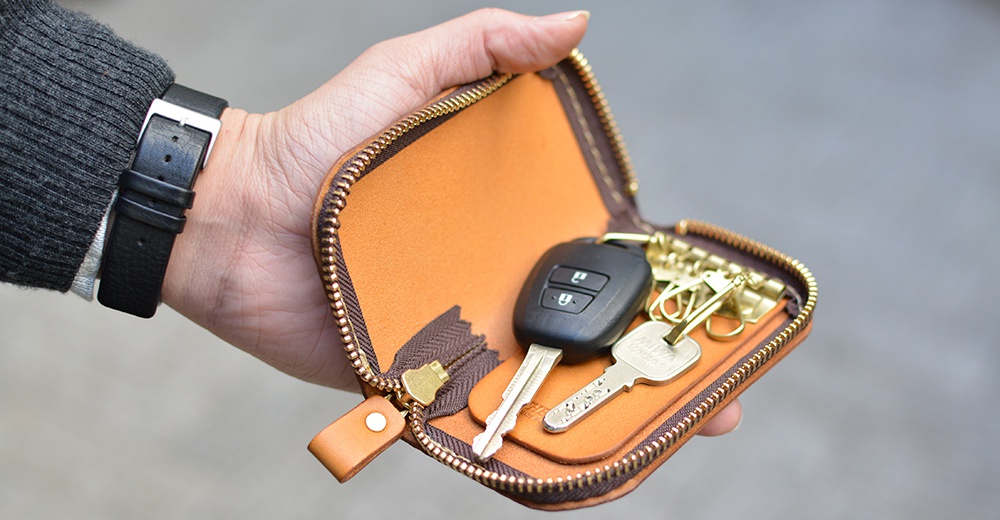 手持皮革鑰匙包，包內有汽車鑰匙及兩枚金屬鑰匙。