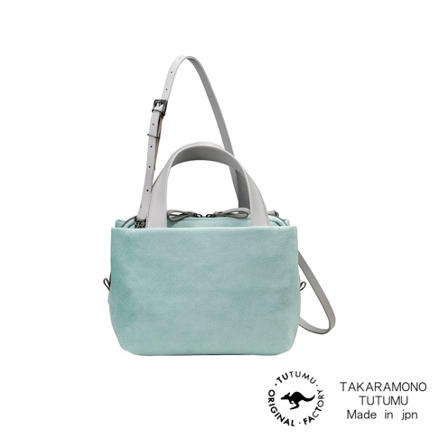 TUTUMU 品牌 Suede tre tote 方形兩用托特包，採用淺藍綠色絨面材質，配有白色皮革提把及可調式斜背帶，搭配底部黑色無尾熊圖案的「ORIGINAL FACTORY」標誌及「TAKARAMONO TUTUMU Made in jpn」文字。