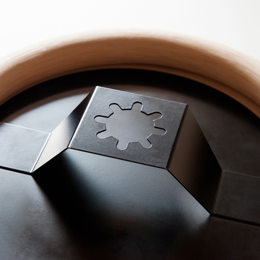 wawa藤編圓鏡的背面，展示了金屬掛鉤的特寫，掛鉤為黑色，帶有六瓣花狀鏤空設計，固定在圓形鏡面和淺木色藤編邊框上。