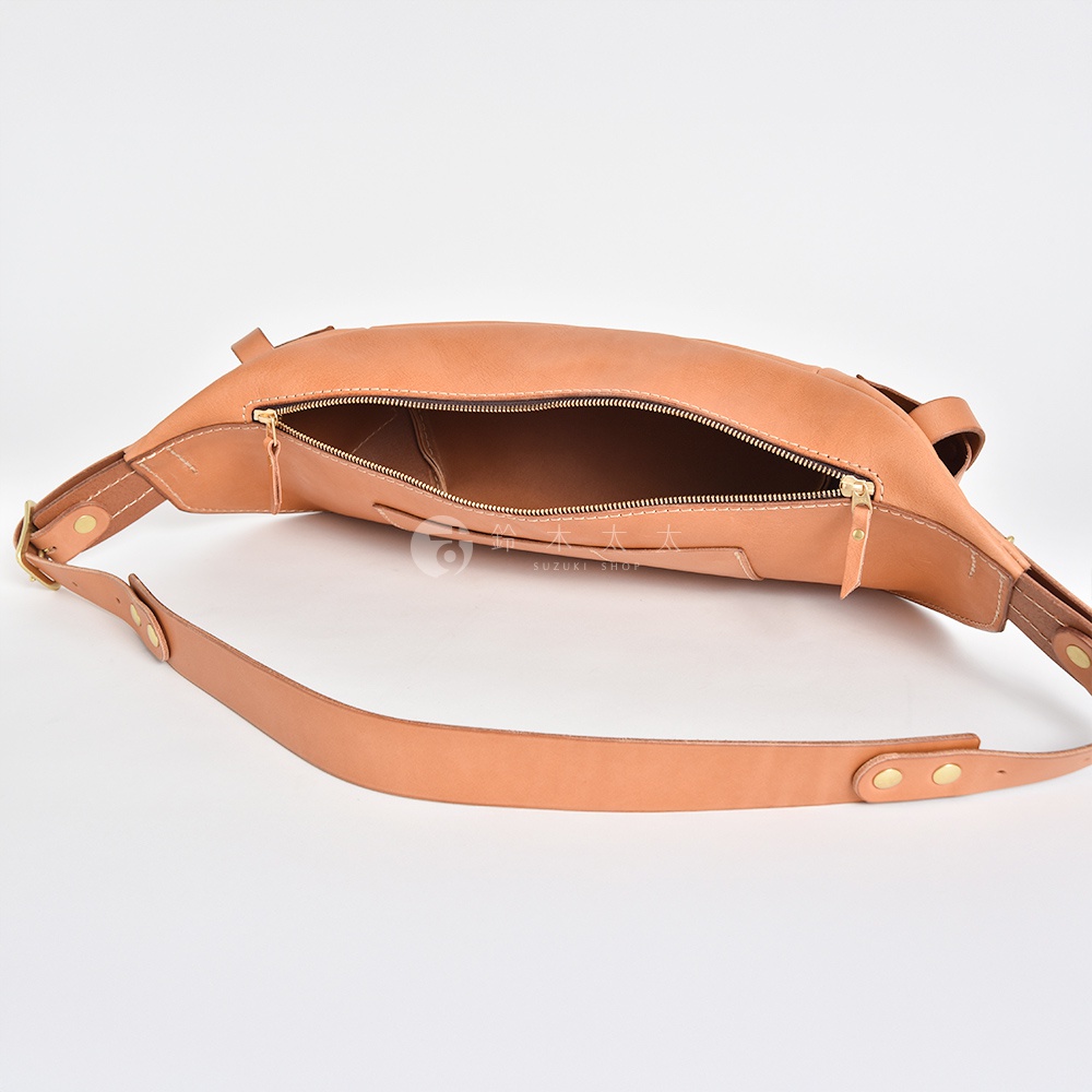 日本HERZ職人手作淺棕色皮革大容量斜背包，拉鍊開口，展現內部細節，搭配金屬釦飾和皮革肩背帶，背景為白色。
