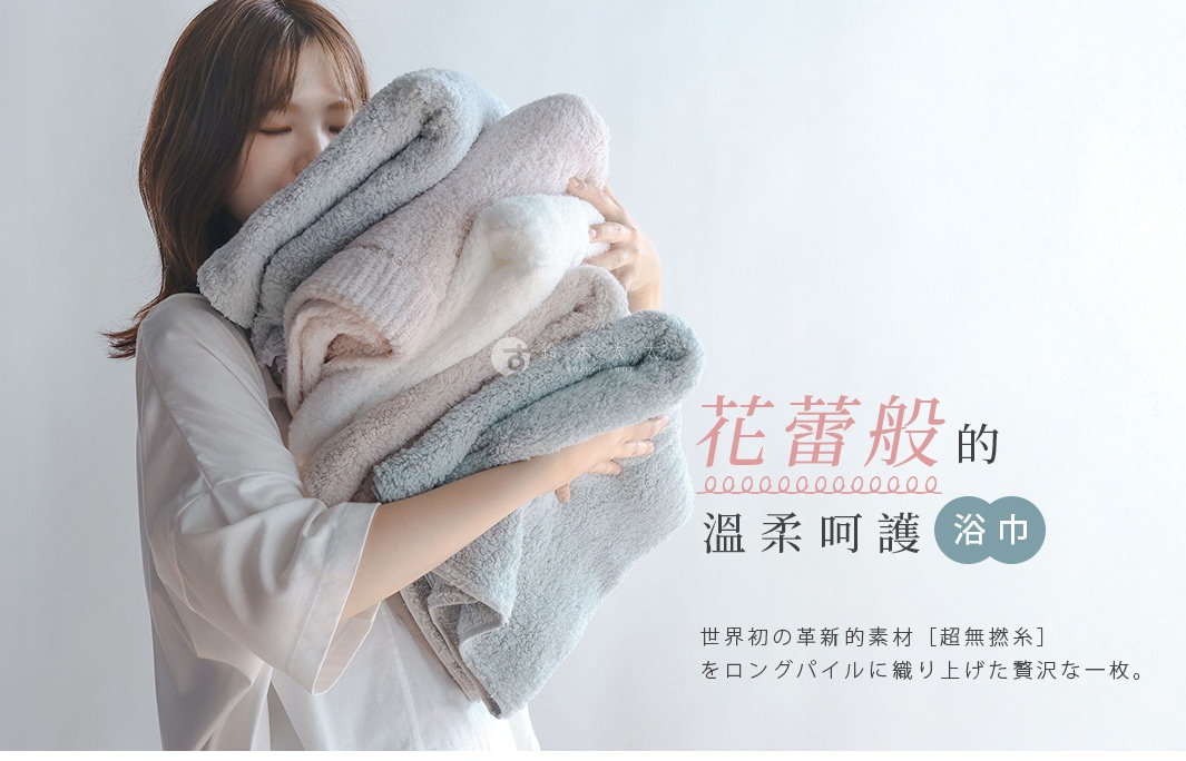 一個女子抱著幾條蓬鬆柔軟的毛巾，上面有日文標語。