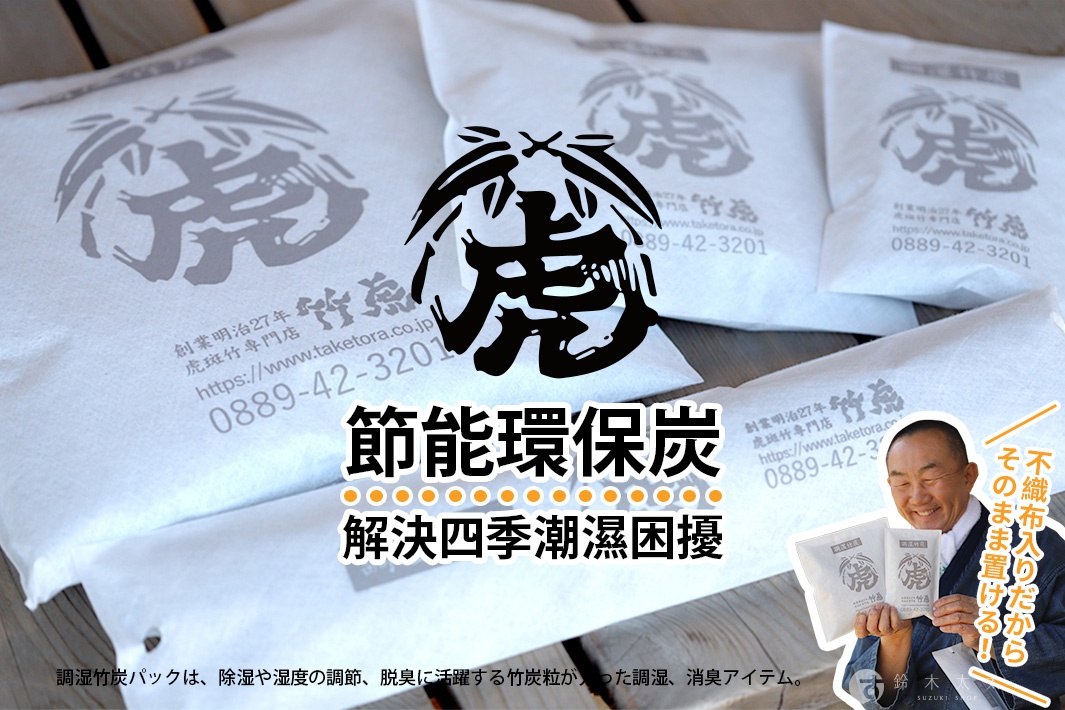 白色無紡布包裝的孟宗竹炭，印有虎形圖案和品牌資訊，堆疊擺放，部分包裝上印有中文標語「節能環保炭 解決四季潮濕困擾」，背景為木質桌面。