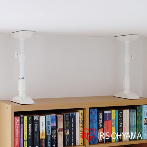 兩個白色塑膠傢俱防倒伸縮固定棒，分別固定在天花板與書櫃頂部，頂端有方形固定座，伸縮桿上有調整旋鈕。
