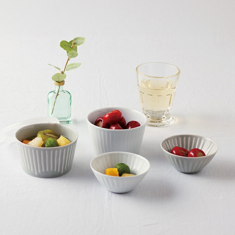 波佐見燒 FUWARI 四件式碗碟，包括三個灰色和白色有條紋的陶瓷碗，分別裝有水果和紅色漿果，以及一個透明玻璃杯，裝有淺黃色液體，旁邊有一個帶有綠葉的矮綠色玻璃瓶。