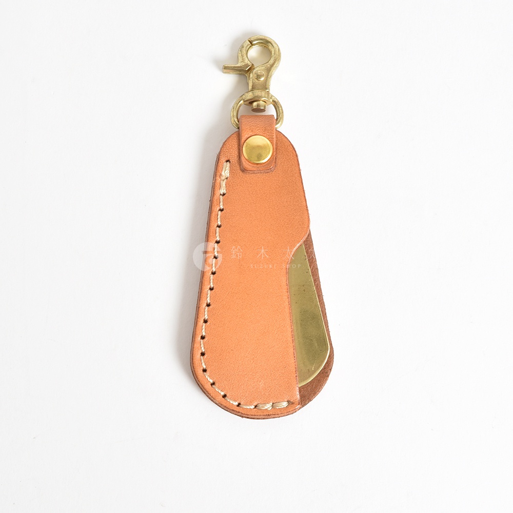職人手作皮革隨身金屬鞋拔，咖啡色皮革外層，搭配金色金屬鞋拔，整體以縫線固定，頂端有金色龍蝦扣，方便隨身攜帶。