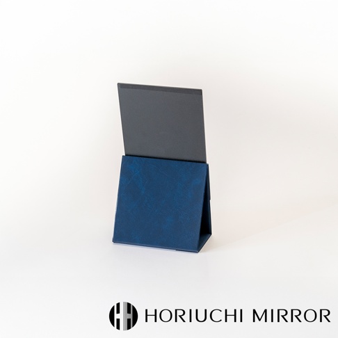 NAPURE桌上型2Way折疊化妝鏡，採用深藍色紋理皮革外觀，鏡面為黑色，鏡架可折疊成A字型站立，具備雙面鏡功能。