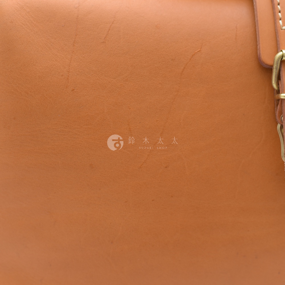 職人手作皮革軟式杜勒斯包，呈現自然棕褐色皮革紋理，帶有金屬扣環細節。