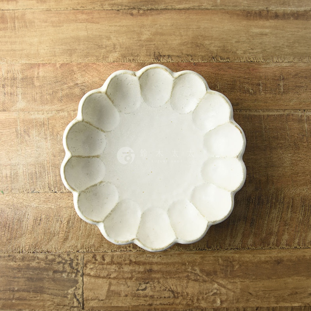 一個24公分的美濃燒粉引沙拉盤，呈現花瓣狀的輪廓，盤面為米白色，帶有陶瓷材質的質感，置於木紋桌面上。