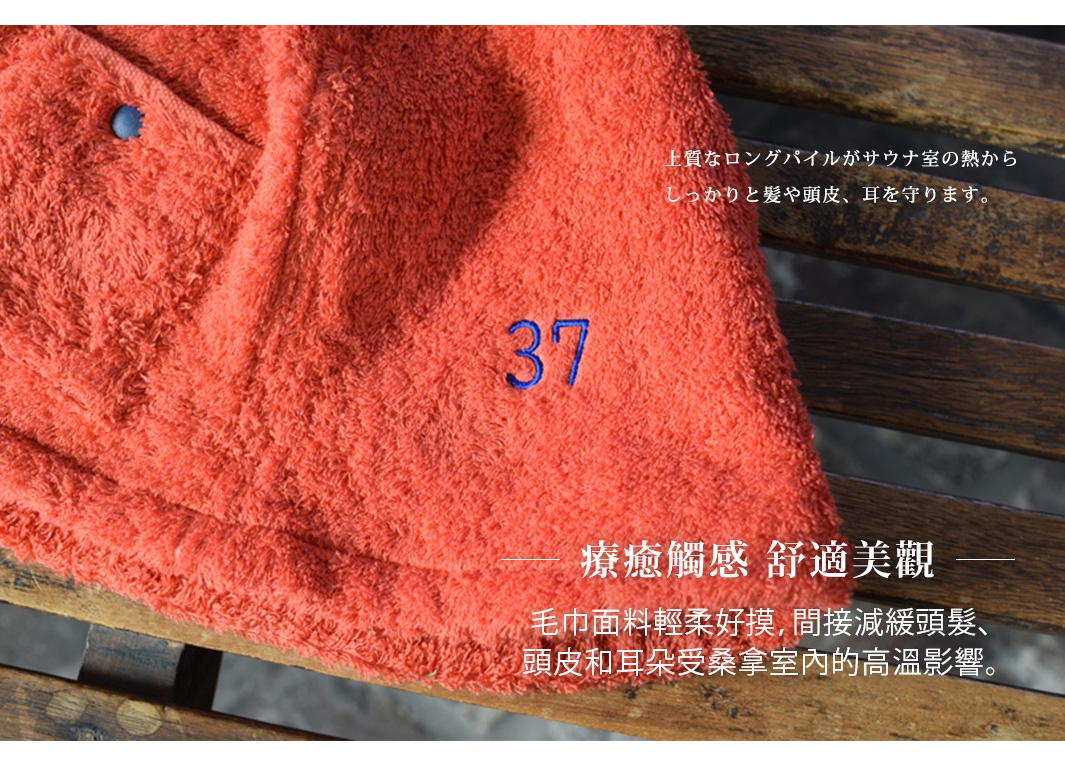 珊瑚橘色毛巾，材質柔軟，繡有藍色數字「37」，一側有藍色鈕扣。