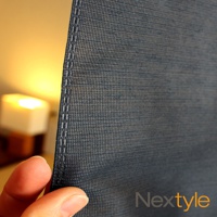 深灰色網狀材質的門簾，帶有清晰的縫線邊緣，背景有模糊的暖色光源。