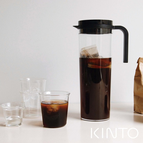 高身透明玻璃冷泡壺，內有咖啡包浸泡深褐色液體，搭配黑色壺蓋及手把。壺旁有裝有冰塊的玻璃杯及裝有冰咖啡的玻璃杯。
