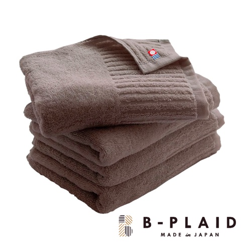 一疊深棕色 RIB 今治浴巾，表面有細緻的直條紋理，頂部一條浴巾上別有紅色、藍色與白色條紋的織標。