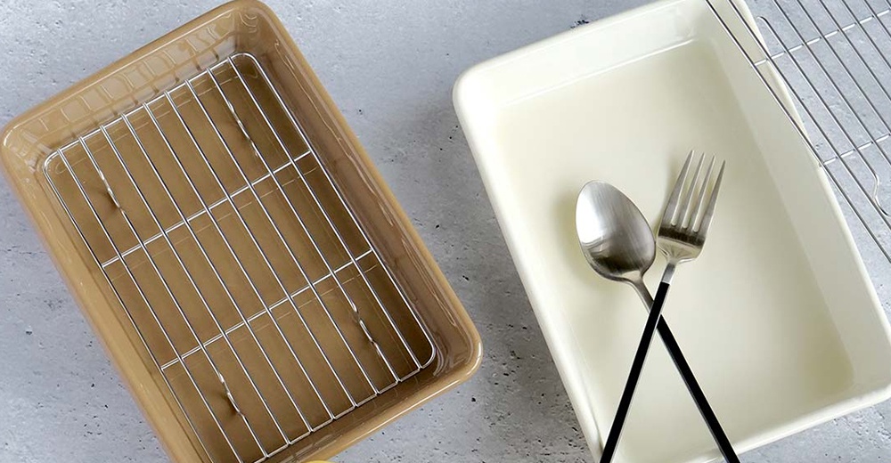 兩個美濃燒釉彩萬用長方烤盤，一個為淺棕色，內附銀色金屬網架；另一個為米白色，盤中放著一個銀色湯匙和一個銀色叉子。