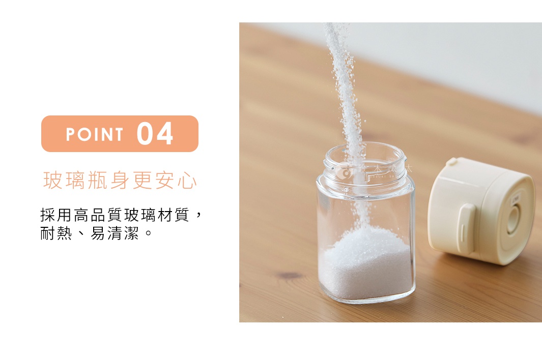 透明玻璃瓶身裝有白色細砂糖，瓶口有細砂糖沿著管狀結構落下，旁邊有一個奶油色塑膠蓋。