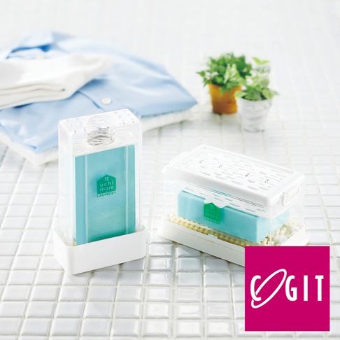 兩個透明塑膠盒，分別裝有淺藍色洗衣皂和白色刷子。其中一個盒狀立式，淺藍色洗衣皂內嵌彈簧；另一個盒狀扁平，淺藍色洗衣皂上疊有白色刷子。背景為白色磁磚，以及一疊淺藍色和白色衣物。