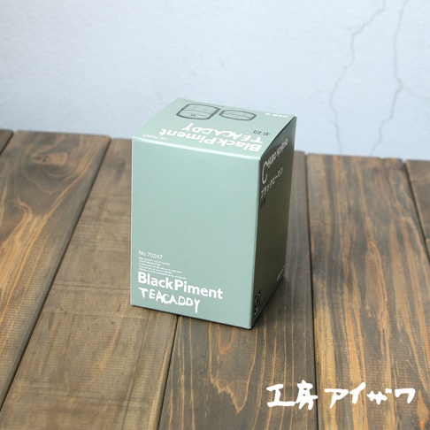 淺綠色紙盒，上面印有白色文字「Black Piment TEACaddy」及產品編號 No.70247，部分日文標示，置於木紋桌面上。