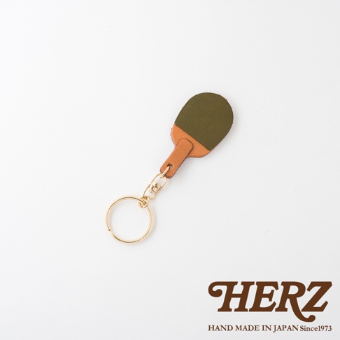 職人手作皮革桌球拍造型鑰匙圈，由咖啡色與墨綠色皮革拼接而成，搭配金色金屬掛環與鍊條，簡約設計。