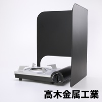 L型折疊擋油板，由金屬製成，呈現啞光黑色。擋油板呈L形，圍繞著一個銀灰色的便攜式瓦斯爐。爐體為黑色，設有黑色旋鈕。