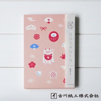 粉紅色和紙御朱印帳，印有白色招財貓、紅色達摩、藍色與紅色日式扇子、紅色花朵、白色烏龜、紅色紙鶴等多種可愛吉祥物圖案。