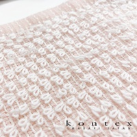 粉色毛巾局部特寫，織有規則排列的白色立體織紋，材質柔軟，呈現細緻的編織紋理。