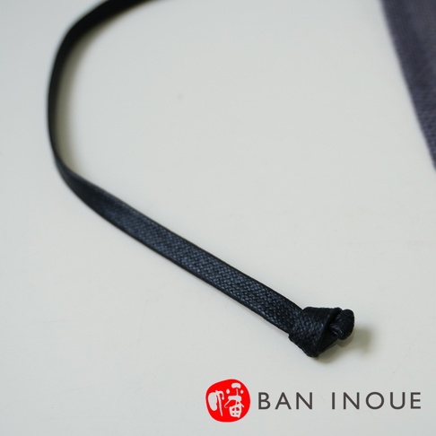 黑色細繩，繩頭打結，布料紋理可見。