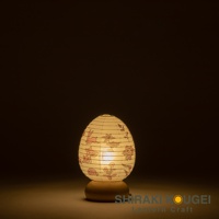 日式雞蛋造型紙燈，燈罩為白色，印有粉色兔子和花卉圖案，下方為木質底座，燈光溫暖。