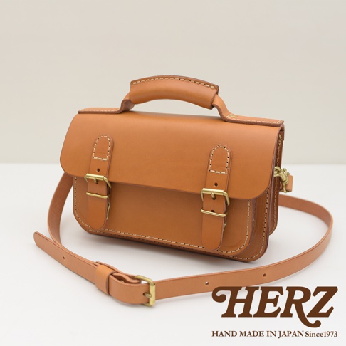 職人手作皮革雙扣兩用迷你肩背包，採用天然棕色皮革，附有金屬釦環和可調式肩帶，設計簡約。
