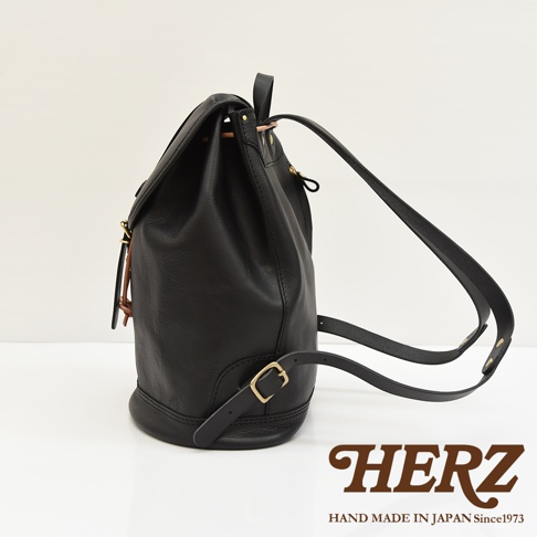 黑色皮革單扣束口後背包，配有可調節肩帶和金屬扣件，展現職人手作質感。