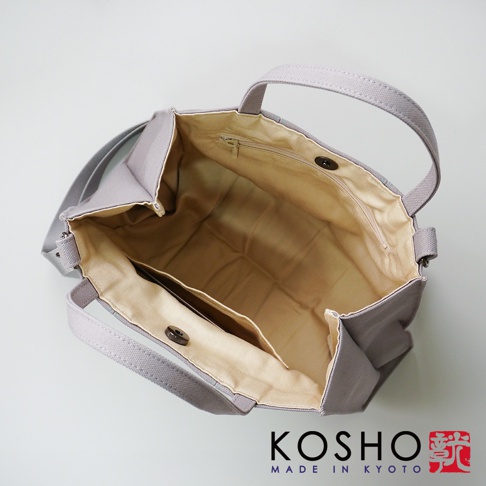 灰色棉帆布扇形托特包，內部有拉鍊開合主袋、內袋和磁釦開合隔層。包包有兩條提把和一條肩帶。