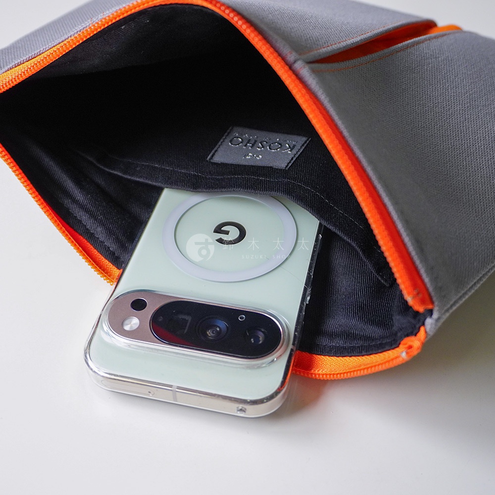 灰色的京都KOSHO帆布收納包微開，內部黑色襯裡印有品牌標籤，一台背面裝有MagSafe磁吸環的淺綠色Google Pixel手機正放置在袋口處。