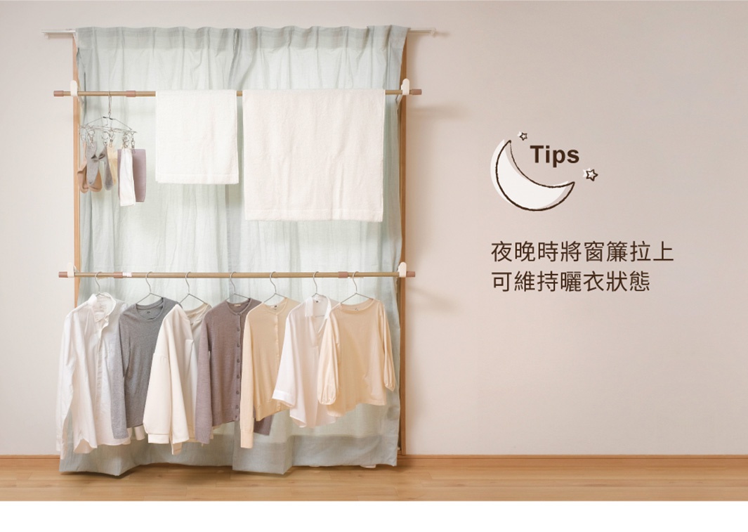 木紋頂天立地曬衣架，設有兩層掛桿，上方掛著兩條白色毛巾，下方掛著多件淺色衣物。