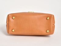 職人手作皮革兩用迷你口金單肩包 (CW-7) 的底部，呈現光滑的棕褐色皮革材質，設有四個黃銅色的金屬腳釘，用於保護包底。