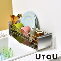 不鏽鋼窄型碗碟瀝水架，附有瀝水盤，架上擺放著木製餐具、綠色與粉紅色杯子、灰色與棕色馬克杯，以及兩個淺藍色盤子。