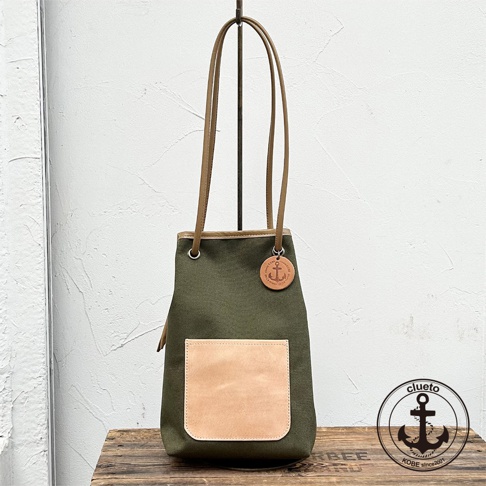 神戶clueto品牌墨綠色尼龍束口肩背包，飾有義大利皮革口袋和錨形吊飾，搭配長皮質提把。
