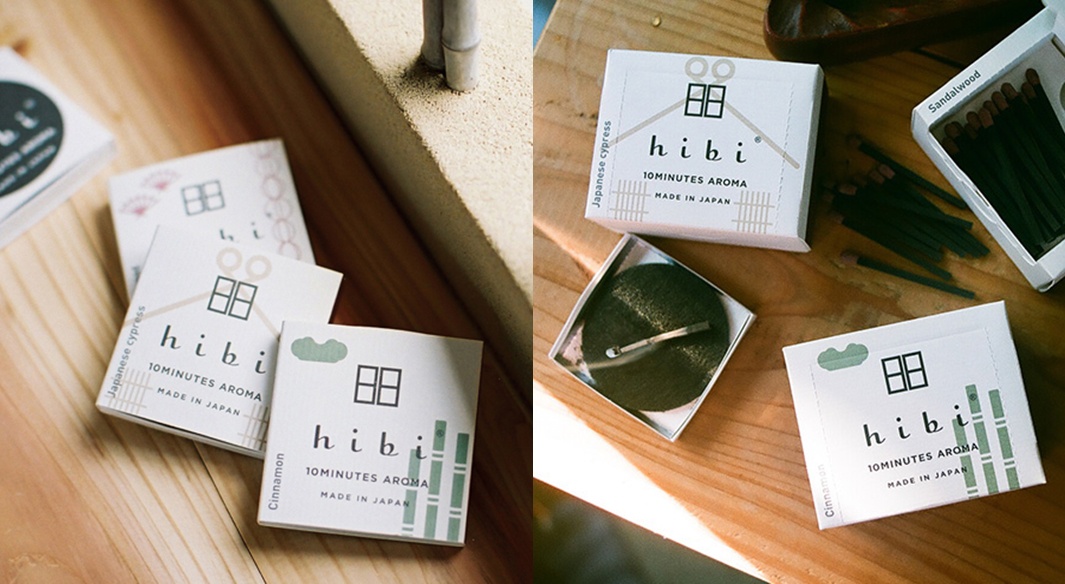 和風限定款香氛火柴禮盒，包含三種香味。白色紙盒上印有「hibi」品牌名稱、日式窗格圖案、竹子圖案以及香味名稱（如Japanese cypress、Cinnamon、Sandalwood）。部分火柴為深綠色，火柴頭為淺棕色，散落在木製檯面上。