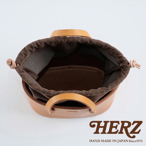 職人手作皮革束口手提包，天然皮革材質，可見圓形提把與束口設計，內裡為深棕色布料，整體呈現自然光澤。