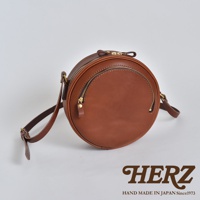 職人手作皮革小圓包，採用圓潤的設計，主體為棕色皮革，配有金色拉鍊。包身設有兩個拉鍊口袋，肩帶可調節。