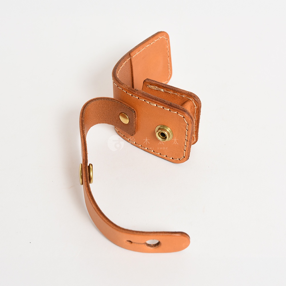 淺棕色皮革製成、附有原子釦的腰間小物收納包，設計簡潔，可掛於腰間。