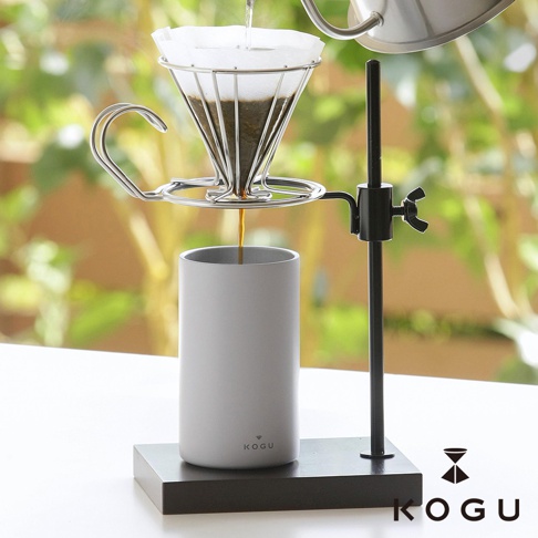 KOGU 珈琲考具 日製高度可調節咖啡手沖架，將濾杯架在手沖架上，正進行咖啡沖泡，濾滴從濾杯流入手沖架下的白色馬克杯中