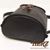 職人手作黑色皮革單扣束口後背包，圓潤底部，頂部束繩設計，搭配金屬釦環。