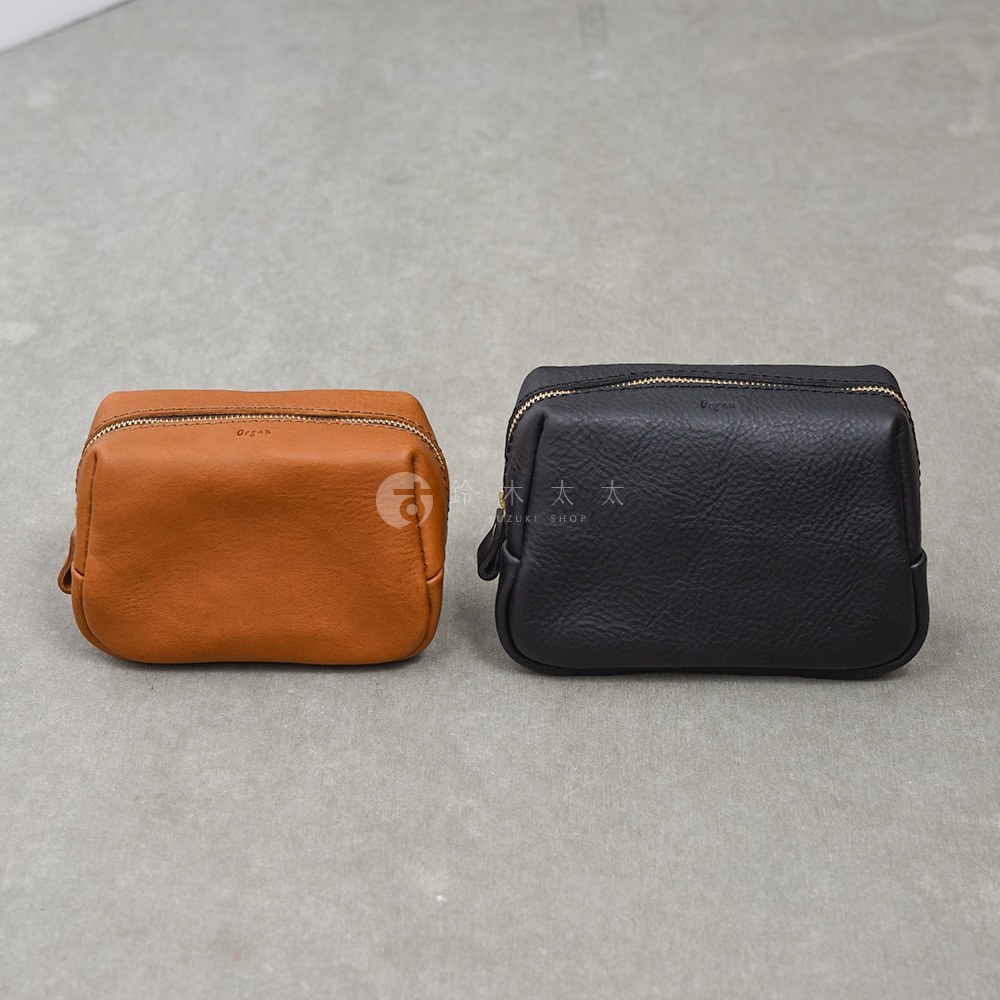 這是一張正面視角照片，畫面中並排擺放了兩個日本 HERZ Organ 系列職人手作皮革收納包。左側為棕色平滑皮革款式，右側為黑色紋理皮革款式，兩者皆為長方形拉鍊設計，正面上方印有細緻的品牌標誌。