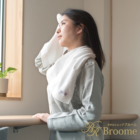 一名女子以白色今治純棉菱紋長毛巾擦拭臉部，毛巾垂掛於肩頸。