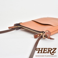 職人手作皮革直式隨身單肩包，淺棕色皮革，設有拉鍊開合及可調節肩帶，金色拉鍊與銅色鈕扣點綴。