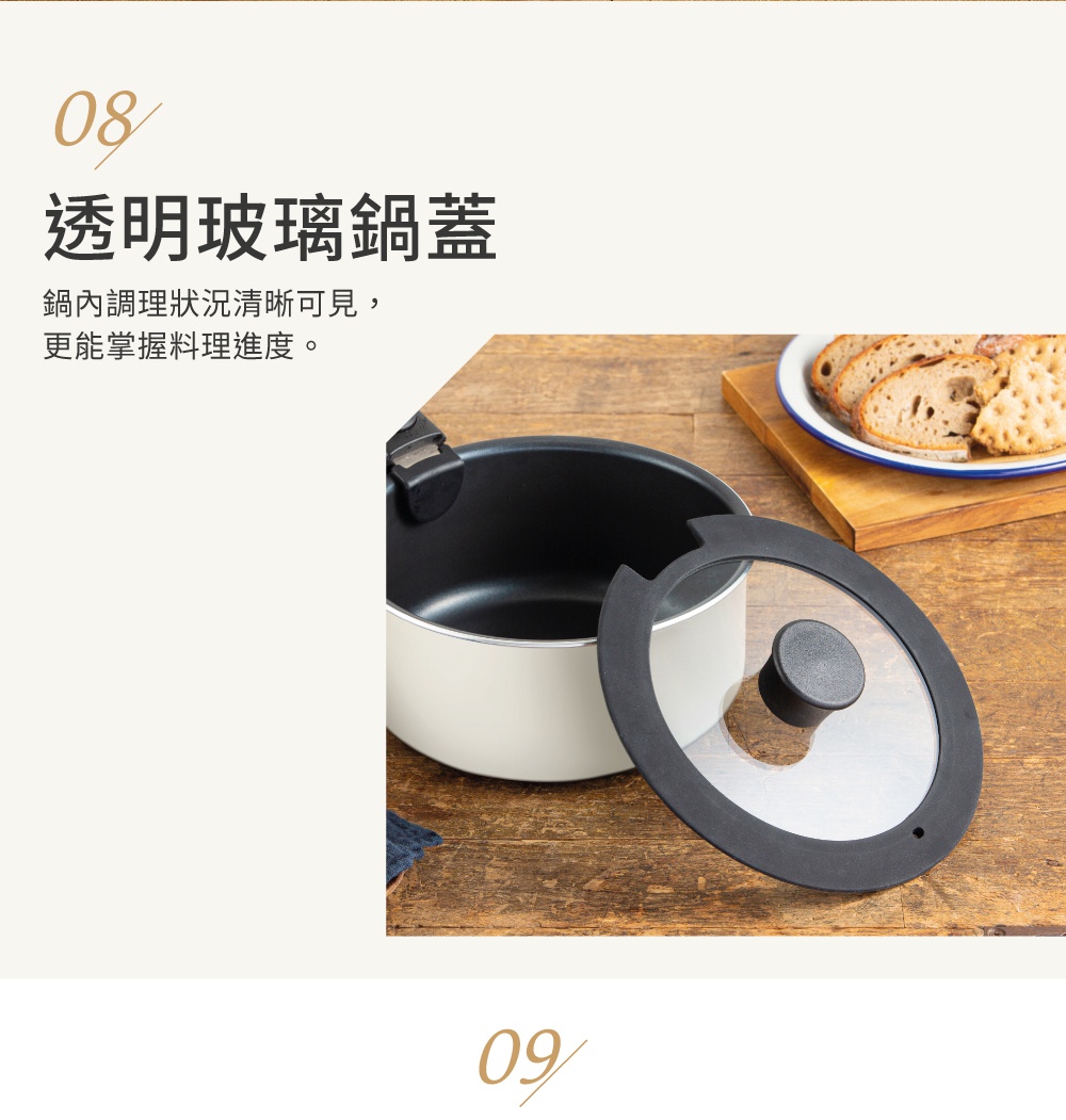 一個附有黑色矽膠邊緣和黑色提鈕的透明玻璃鍋蓋，旁邊是一個淺米色的不沾鍋，鍋內有黑色塗層，鍋蓋放置在鍋的旁邊。