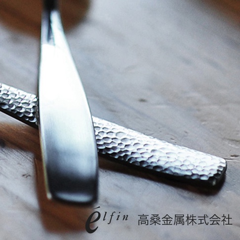 兩支日製不鏽鋼湯匙，一支勺頭光滑，另一支勺柄有錘目紋，整體為銀色金屬質感。