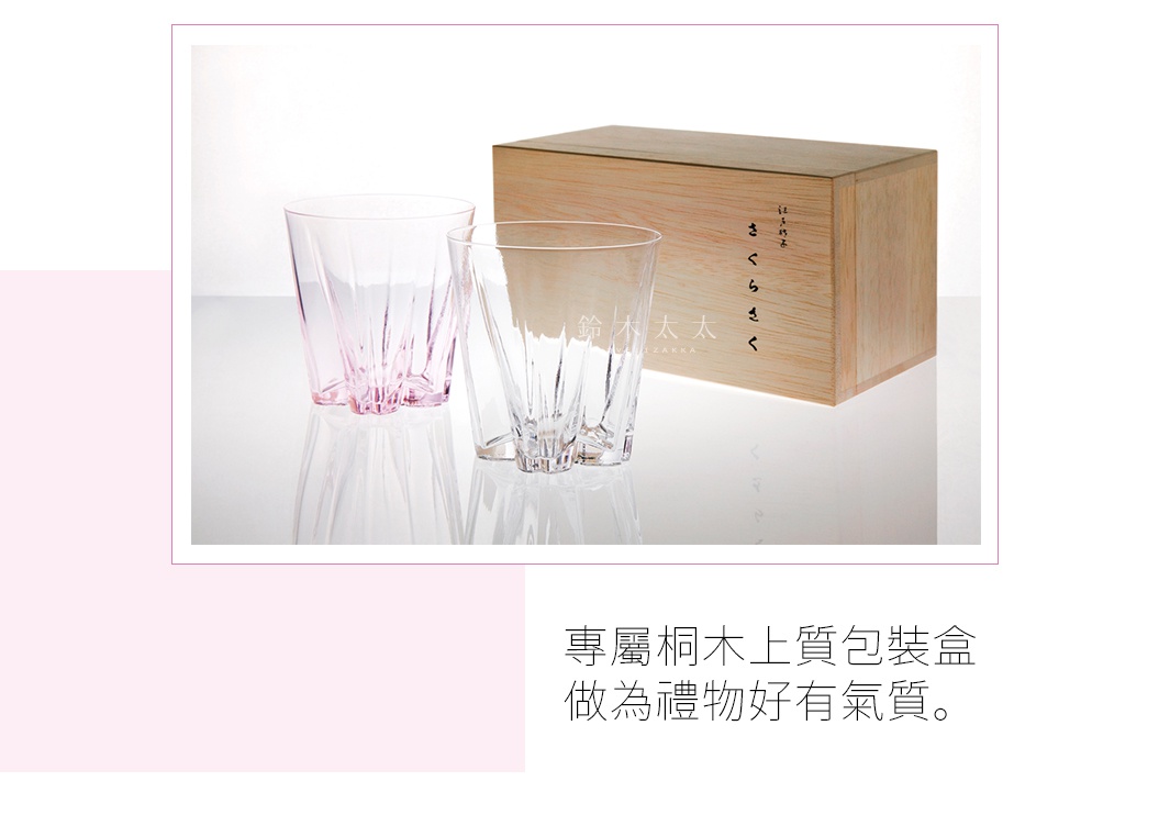 兩個玻璃威士忌杯，一個為淡粉色，一個為透明色，均有放射狀的壓紋。杯子放置在一個淺色木質包裝盒旁，木盒上有日文文字。