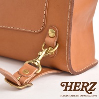 全手工製作的職人皮革迷你後背包，採用原色皮革，搭配黃銅釦具和金屬掛鉤，展現復古精緻工藝。