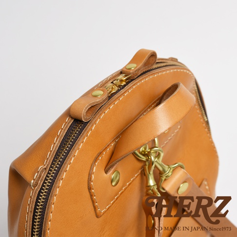 職人手作皮革大開口圓角後背包 R-18，展現自然色澤的皮革材質，搭配黃銅色拉鍊與金屬扣環，縫線細緻，設計簡約。